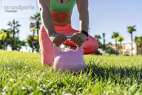 Frau trainiert draußen mit ihrer Kettlebell