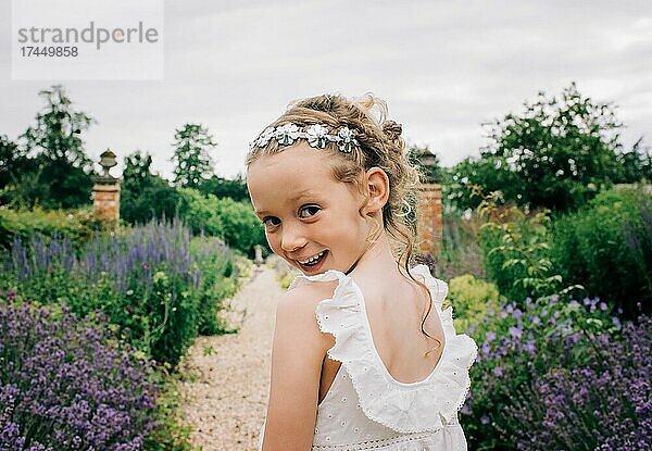 Junges Blumenmädchen lächelt bei einer Hochzeit in einem wunderschönen Blumenfeld