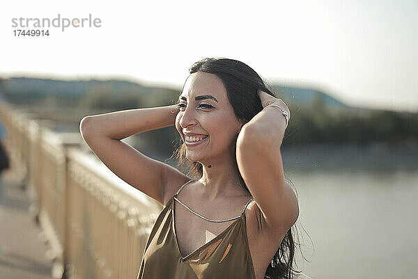 Porträt einer lachenden jungen Frau auf einer Brücke