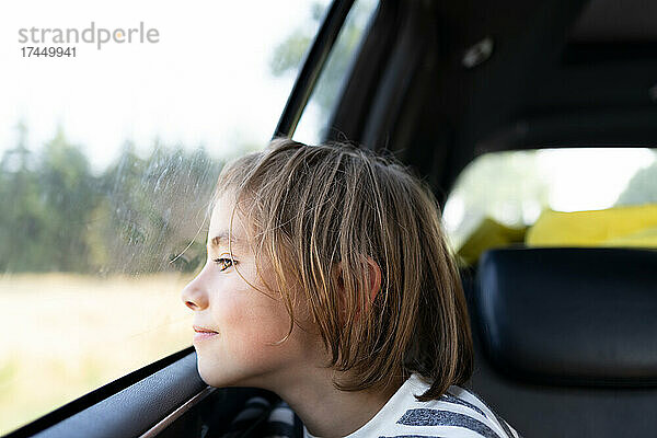 Junge schaut auf einem Roadtrip aus dem Fenster eines Autos