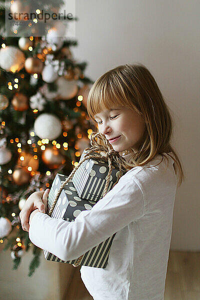 Bild eines Mädchens  das Kisten mit Geschenken umarmt.