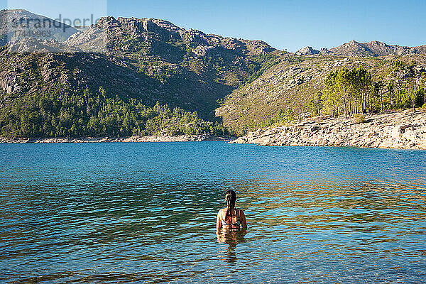 Kaukasische Frau an einem See mit Bergen im Hintergrund