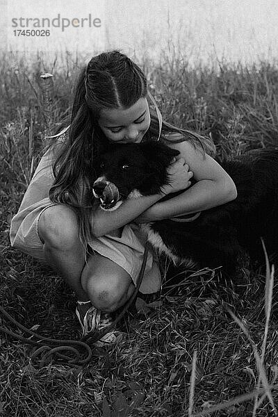 Glückliches Mädchen  das draußen seinen Hund umarmt. Lebensstile und Haustierpflegekonzept.