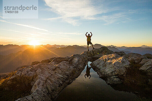 Erfolgreicher Wanderer erreicht bei Sonnenuntergang den Berggipfel.