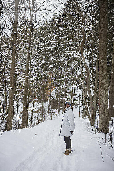 Lächelnde Frau steht im wunderschönen schneebedeckten tschechischen Wald