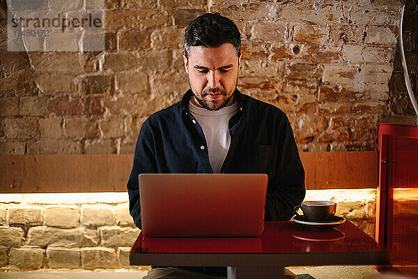 Konzentrierter Geschäftsmann benutzt Laptop-Computer im Café