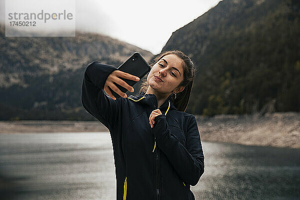 Mädchen macht mit ihrem Handy ein Selfie in den Bergen
