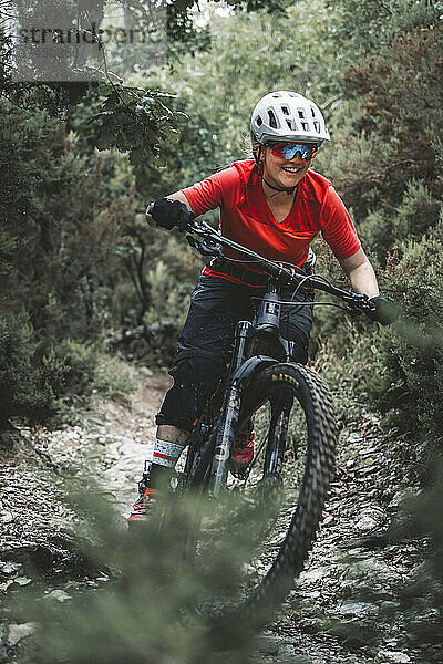 Porträtaufnahme einer jungen Mountainbikerin auf dem Trail