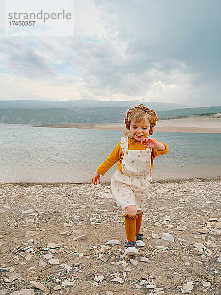 Kleines Mädchen lacht auf einem Hügel in der Nähe eines Bergsees