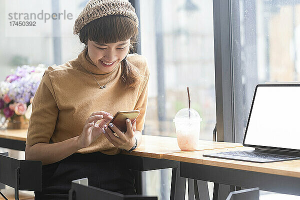 Frau benutzt Telefon im Café.