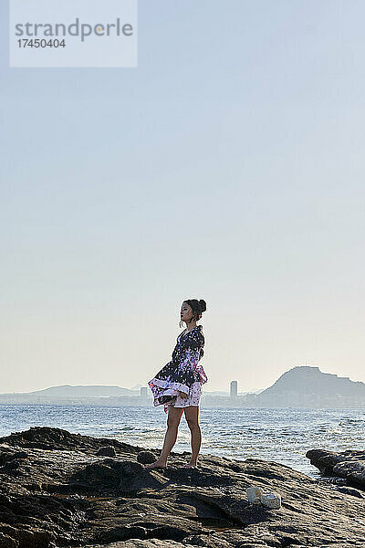 Junge asiatische Frau  gekleidet als Geisha  mit dem Meer im Hintergrund