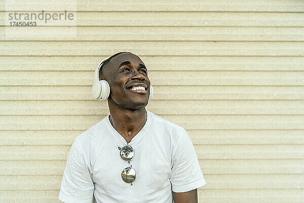 Junger afrikanischer Mann  der über seine Kopfhörer Musik hört