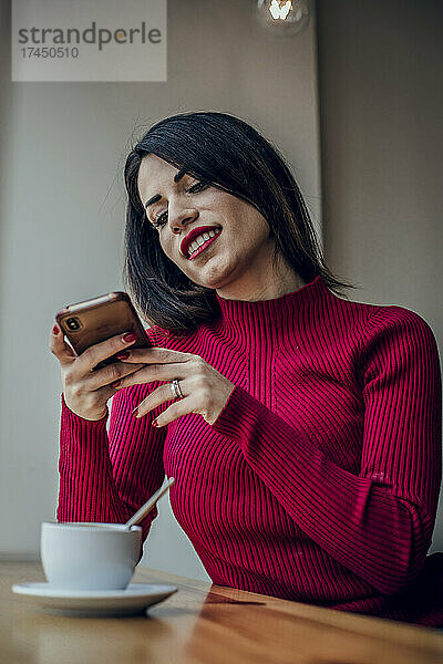 Mädchen macht mit ihrem Mobiltelefon ein Foto in einem Café