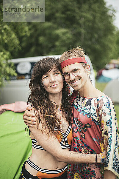 Zwei unkonventionelle Freunde umarmen sich lächelnd und tragen auf dem Festival flippige Kleidung