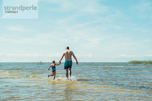 Vater und Tochter schwimmen tagsüber im See.
