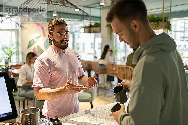 Männlicher Kunde spricht mit Barista