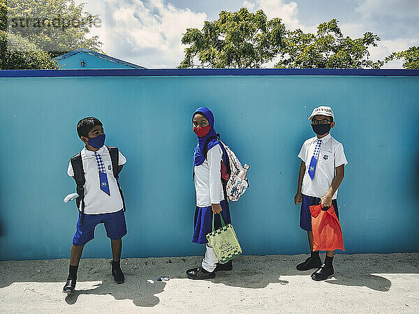 Asiatische Kinder in Schuluniform tragen Schutzmaske