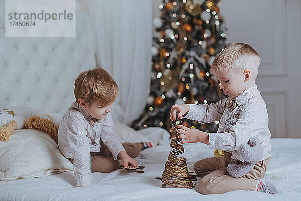 Fröhliche süße Kinderjungen  die Geschenke unter dem Weihnachtsbaum öffnen.