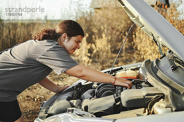 Eine Frau repariert und behebt an einem strahlend sonnigen Tag im Freien ein Auto