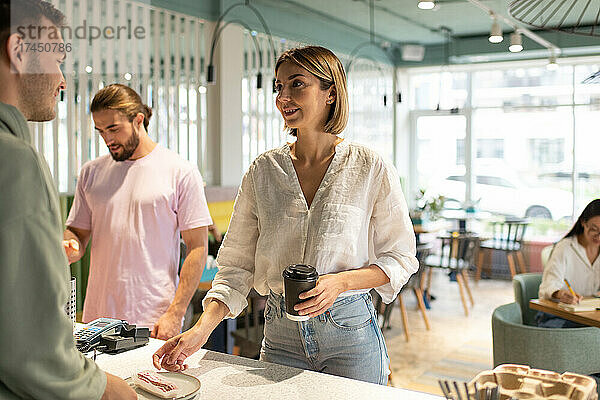 Erwachsene Frau nimmt Bestellung vom Barista entgegen