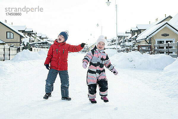 Zwei Kinder haben Spaß beim Spaziergang im Winterdorf.