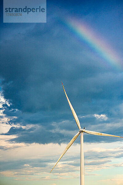 Regenbogen in einem dunklen Himmel über einer Windkraftanlage