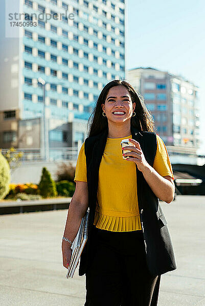 Junge Geschäftsfrau  die auf der Straße läuft und einen Kaffee in der Hand hält