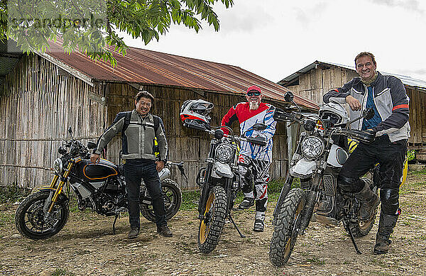 Männer halten mit ihren Motorrädern in einem thailändischen Dorf an