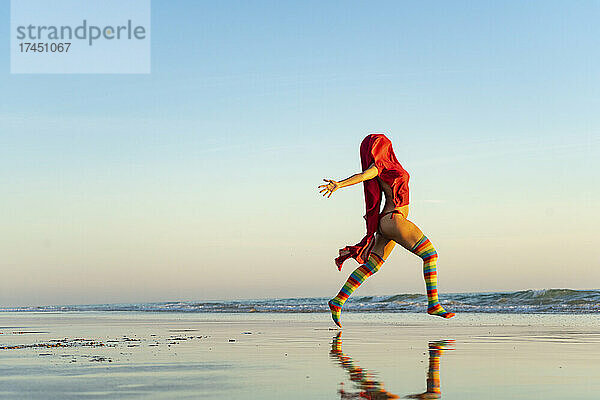 Mädchen läuft in Regenbogenstrumpfhosen frei zum Meer