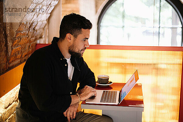 Konzentrierter Geschäftsmann benutzt Laptop-Computer im Café