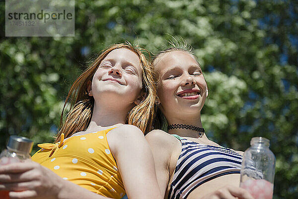 Zwei glückliche Teenager-Mädchen in Badeanzügen im Freien.