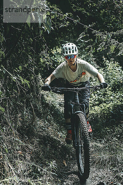 Porträt-Actionaufnahme einer fokussierten Mountainbikerin auf einem Trail