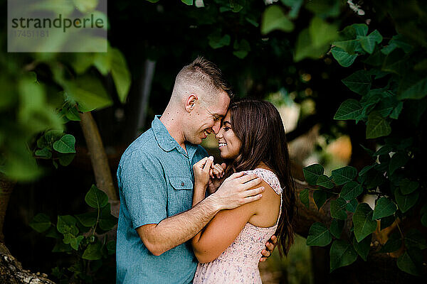Mann und Frau posieren unter einem Baum in San Diego