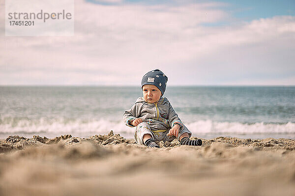 Junge sitzt auf dem Sand vor dem Hintergrund der Ostsee