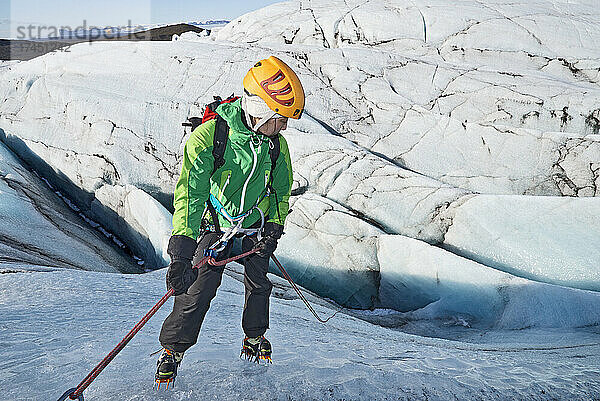 Frau steigt in Gletscherspalte am Svinafellsjökull-Gletscher / Island auf