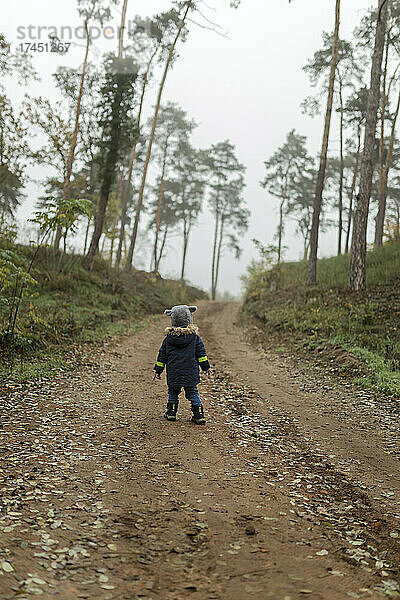 Kleinkind mitten im Wald auf einem Wanderweg bei nebligem Wetter