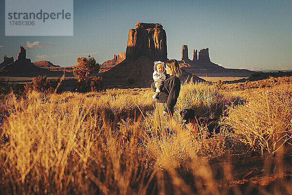Eine Frau mit einem Baby und einem Hund steht im Monument Valley  Arizona