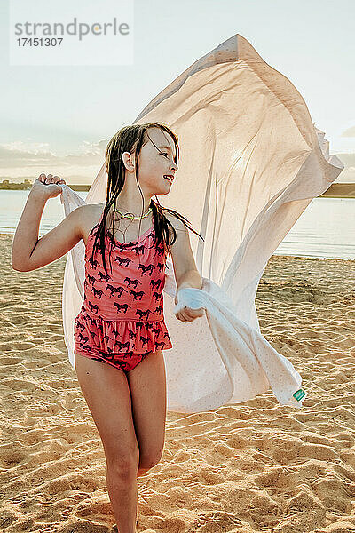 Glückliches junges Mädchen  das Laken als Umhang am See benutzt