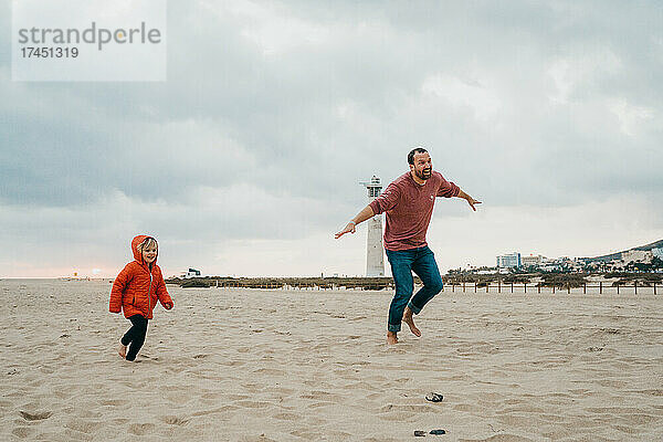Vater und Sohn laufen im Sand am Strand der Kanarischen Inseln