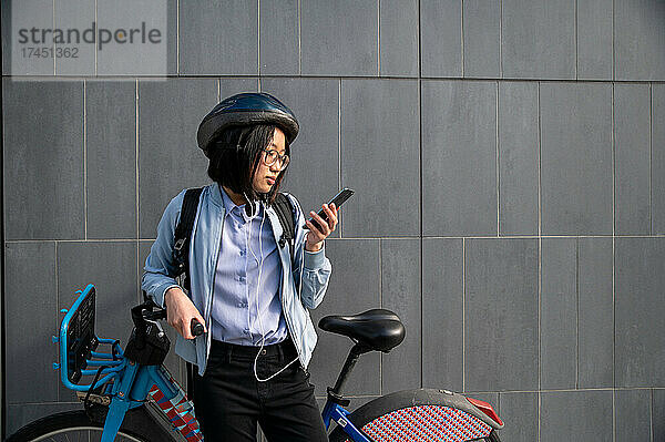 Junger Mensch schaut beim städtischen Fahrradverleih aufs Handy