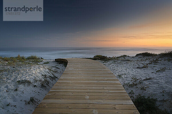 Ruhige Sonnenuntergangsszene mit einem Gehweg über den Stranddünen