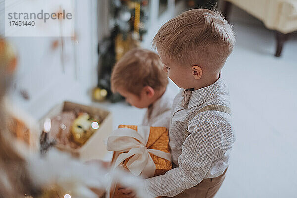 Fröhliche süße Kinderjungen  die Geschenke unter dem Weihnachtsbaum öffnen.