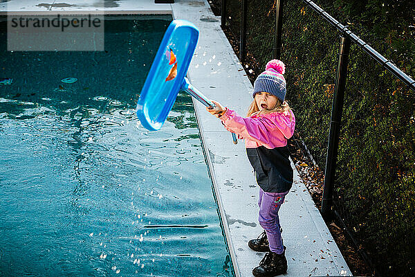 5 Jahre altes Mädchen putzt im Herbst das Schwimmbad