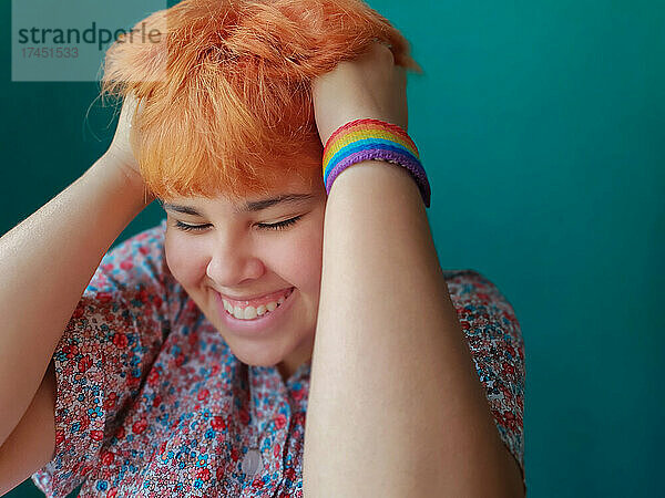 Ein Teenager-Mädchen mit roten Haaren und einem LGTB-Armband lächelt in einem freudigen Moment