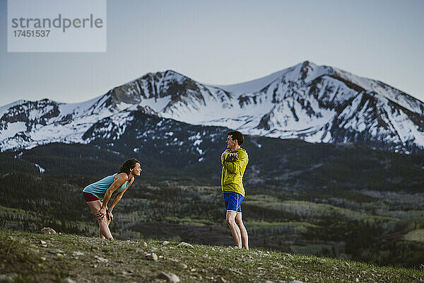 Zwei Freunde machen gemeinsame Dehnübungen vor dem Trailrunning in den Bergen