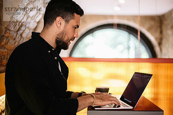 Konzentrierter Mann benutzt Laptop-Computer im Café