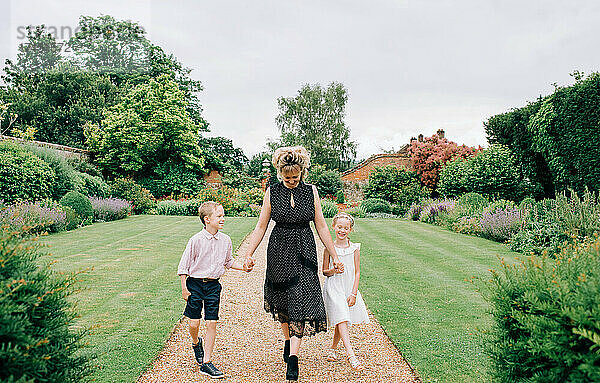 Mutter und ihre Kinder gehen bei einer Hochzeit durch einen wunderschönen Garten