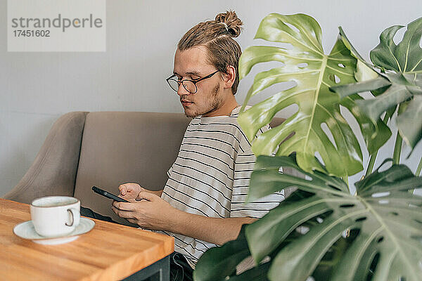 Teenager junger Mann schreibt SMS im Café.
