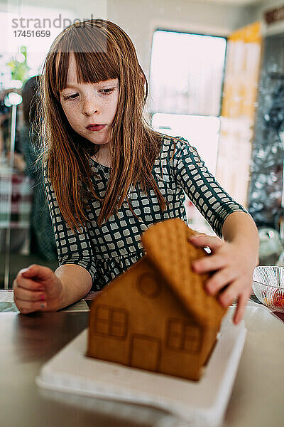 Junges Mädchen baut an einem sonnigen Tag drinnen ein Lebkuchenhaus