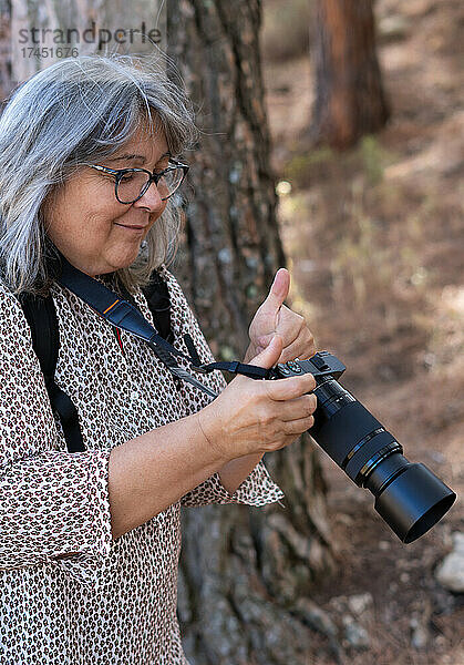 Ältere weißhaarige Frau  die in einem Wald fotografiert